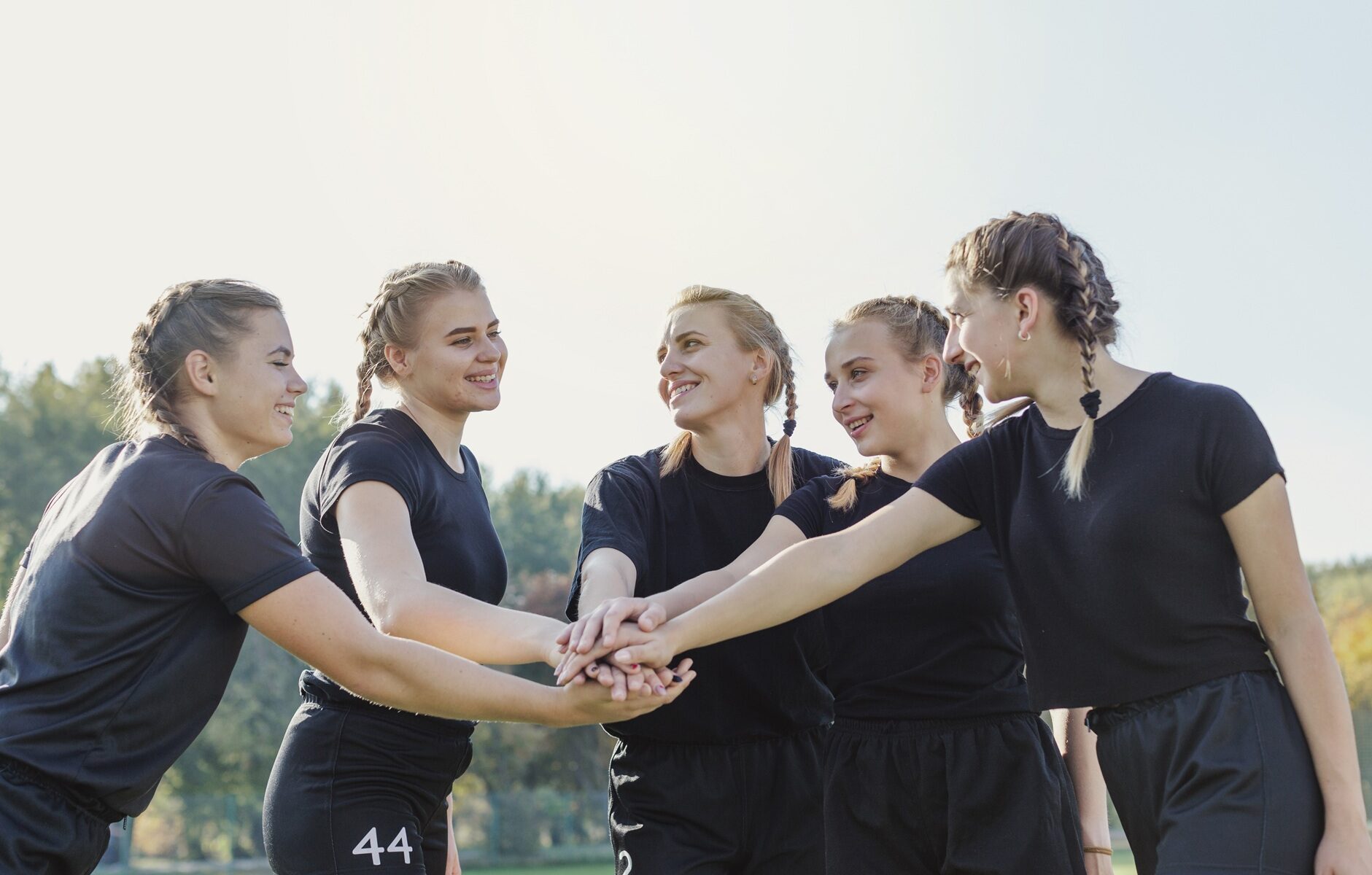 Female sports team putting hands together
